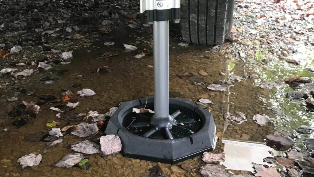 A fifth wheel jack with the best RV jack pads on it protecting it from the muddy puddle 