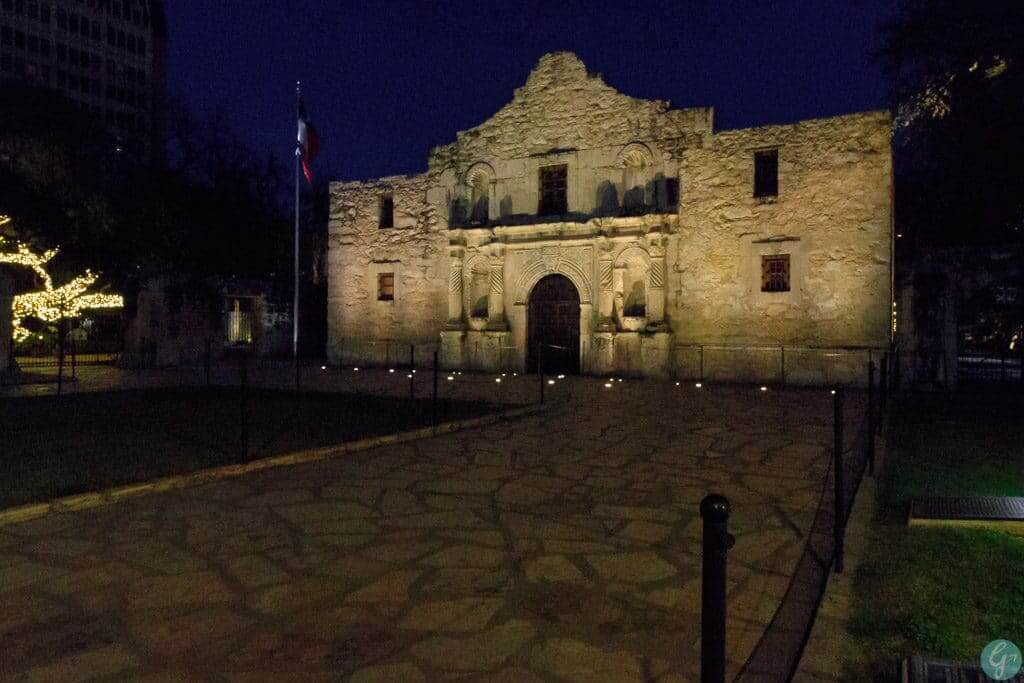 The Alamo at night with lights shining up on it 