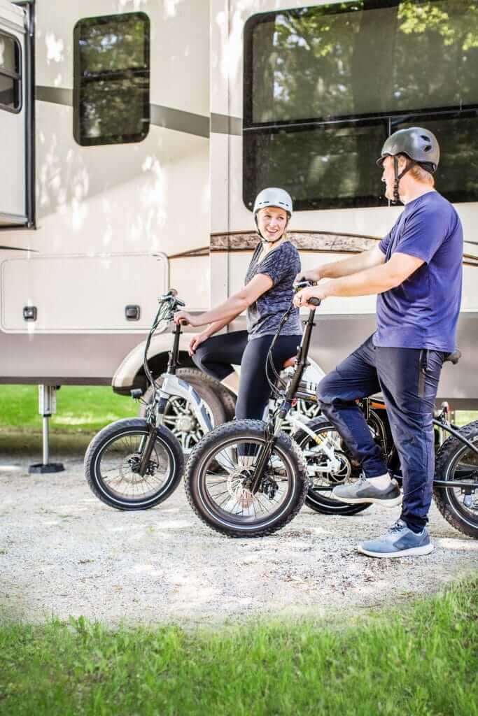 Couple smiling with two Rad Power Bikes in front of their RV. 