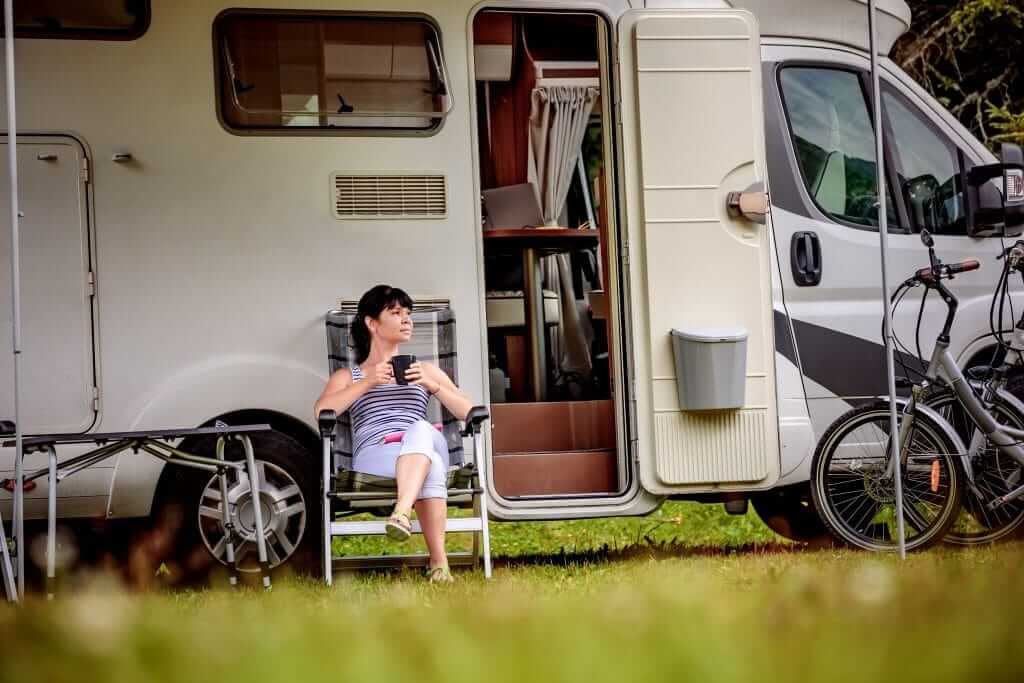 Women sitting in front of her RV after using her campground membership to save money
