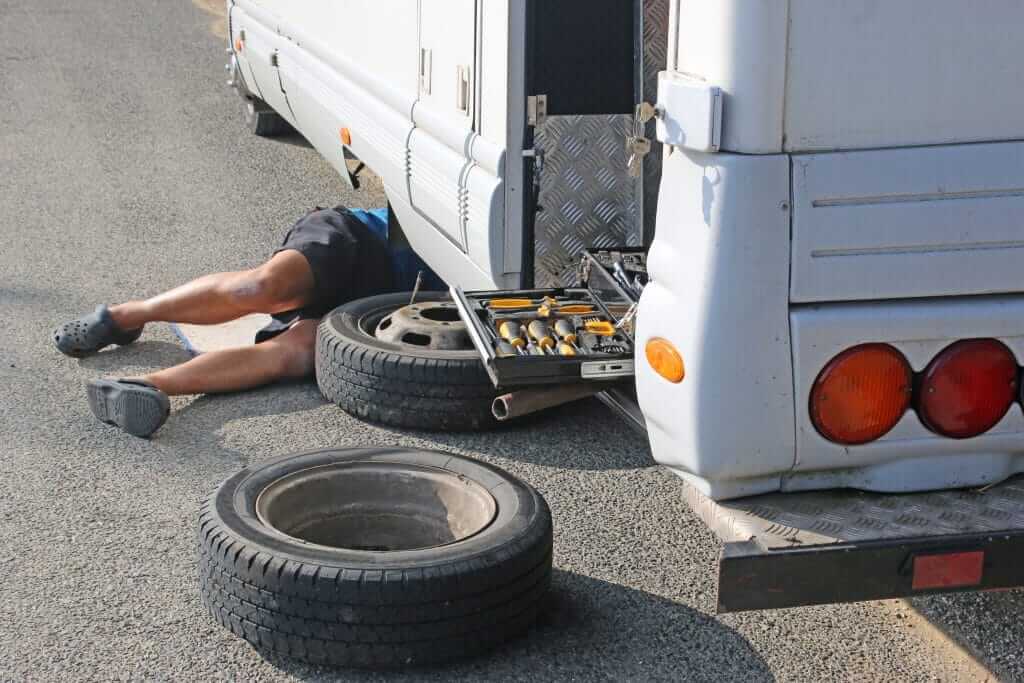 Man under RV changing tire.