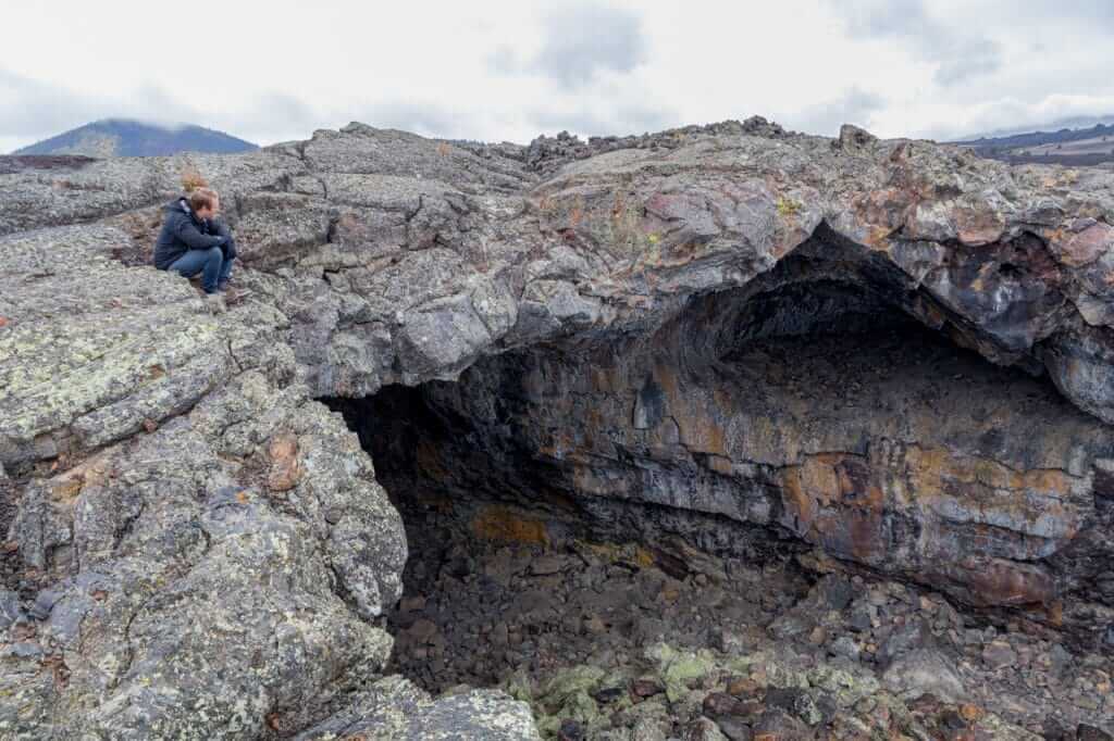 A man sitting on the top of a lava tube, while camping at craters of the moon.