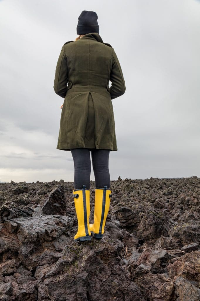 A woman standing on old lava at craters of the moon with cloudy skies behind her 