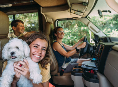 Family smiling from RV as they drive down the road on RV trip
