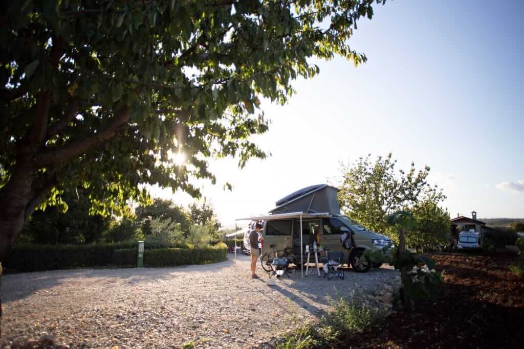 A man standing in front of a pop up camper van with the awning out. They are on a hosts property from the Boondockers Welcome website.