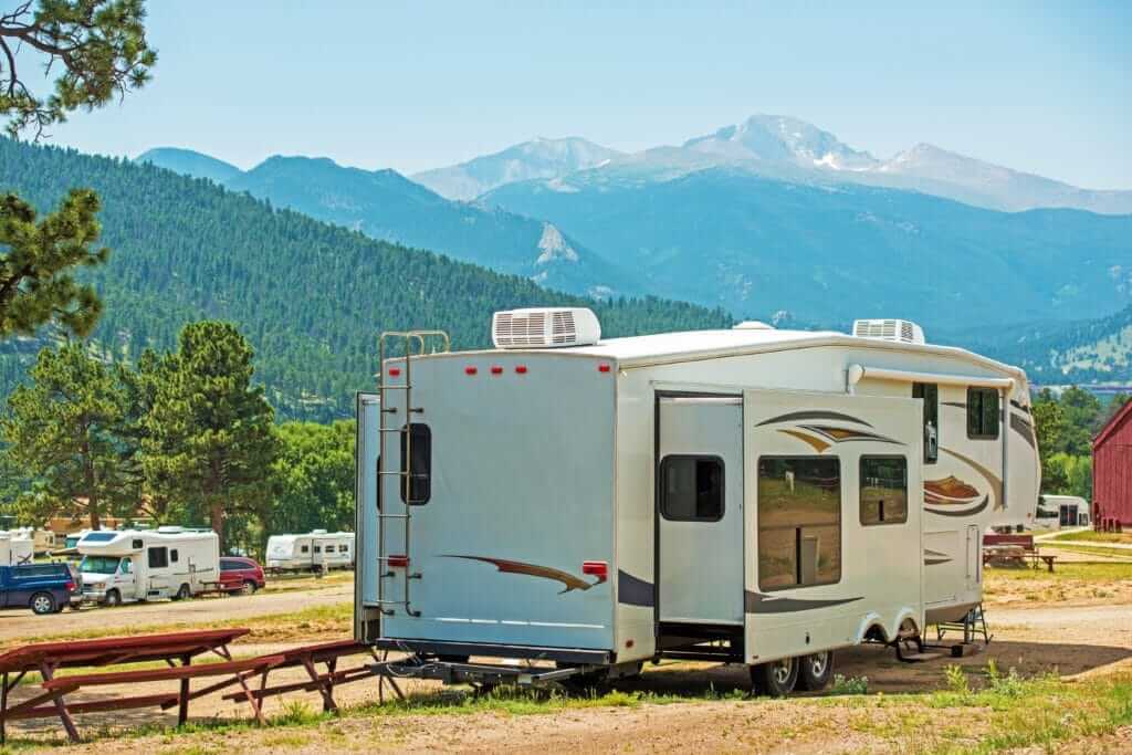 Grand Design Solitude vs Keystone Montana with RV in a campground and view of the mountains