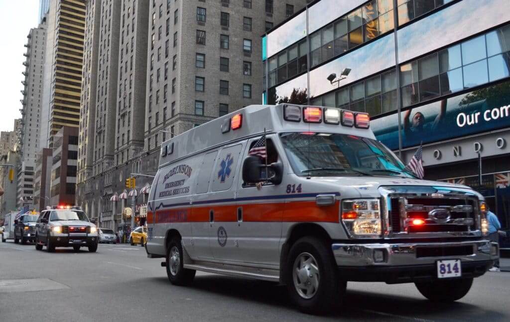 Ambulance driving down the road in a busy city. good sam travel assist will help you get to the hospital in an emergency.