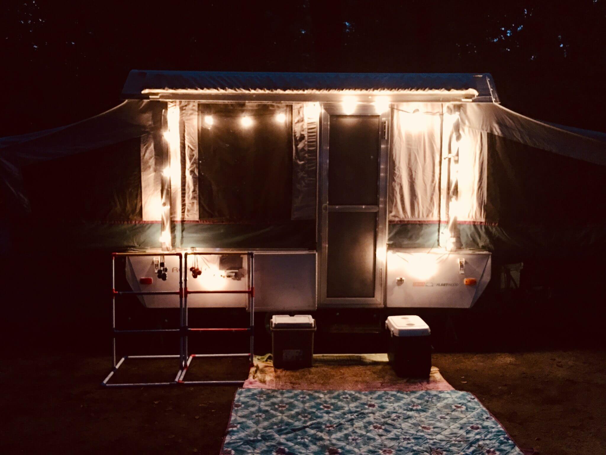 Small camper with bathrooms at night with string lights outside