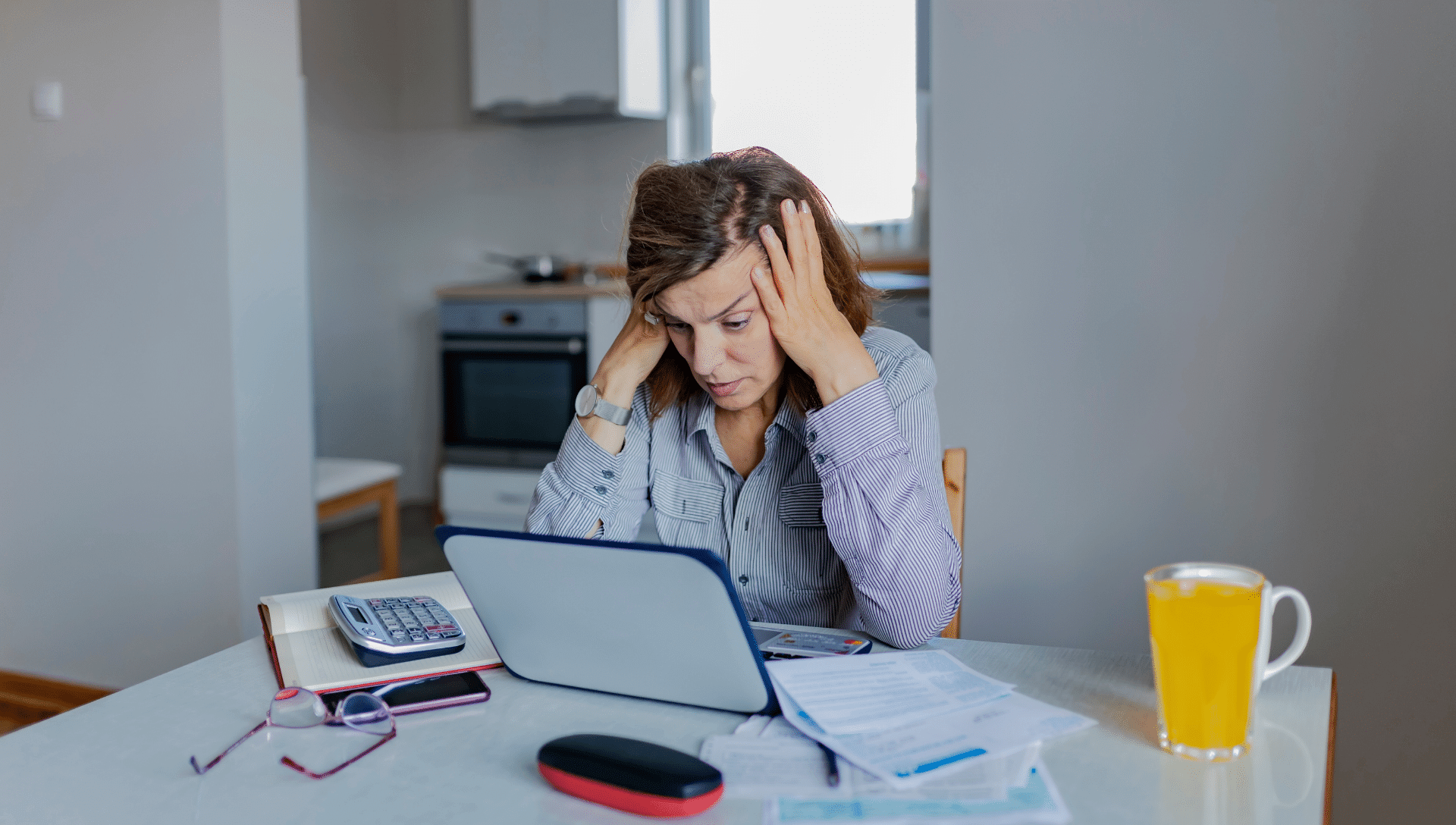 A lady sits in front of her computer with her hands on her head. She is researching RV loans and how to avoid mistakes.