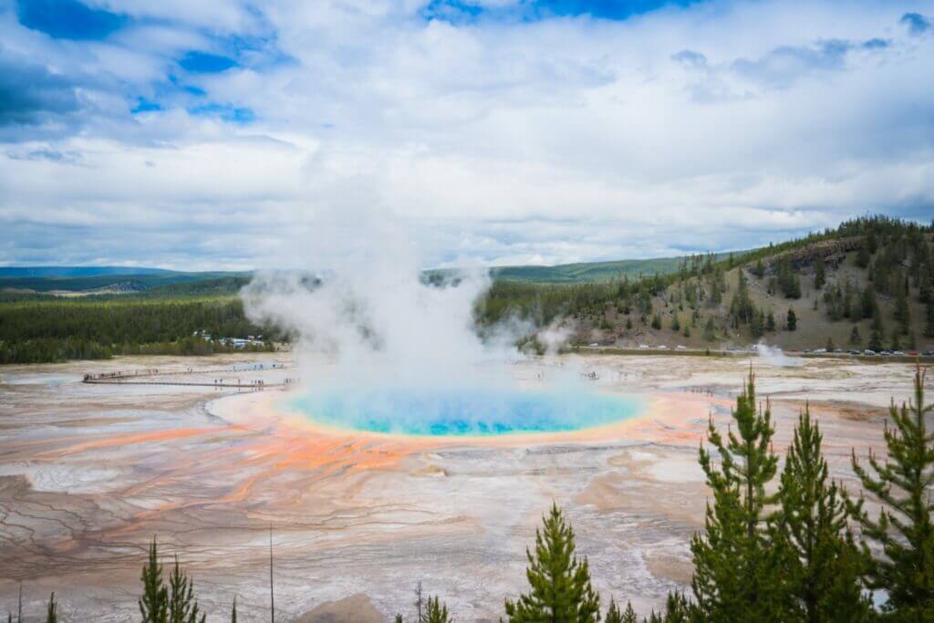Grand Prismatic Spring from far away with the whole spring in view and mountains in the background. To stay close to the spring, you'll want to learn our yellowstone camping reservations tips. 