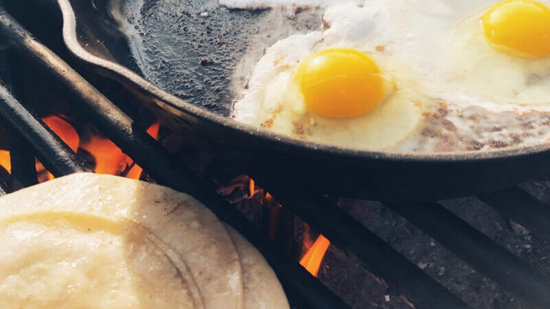 Delicious camping meal breakfast of eggs and tortillas over an open flame.