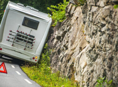 An RV is pulled off the road and against a rock wall with a safety cone in the road behind it. Is RVing safe?