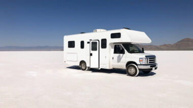 A white self-contained RV is parked in the middle of nowhere white desert, but they don't have to worry! They have everything they need onboard so they don't have to rely on campsite hookups to use the bathroom or shower.