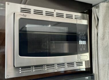 a stainless steel RV microwave mounted above the stove in a travel trailer