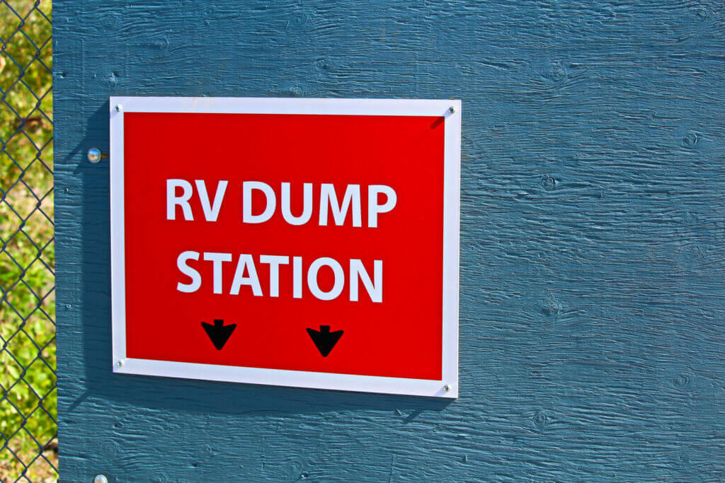 An RV dump station sign on the edge of a building.
