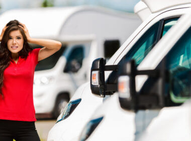 A woman with a red shirt stands in front of a row of RVs and she looks very stressed. Is 2021 the worst year to buy an RV?