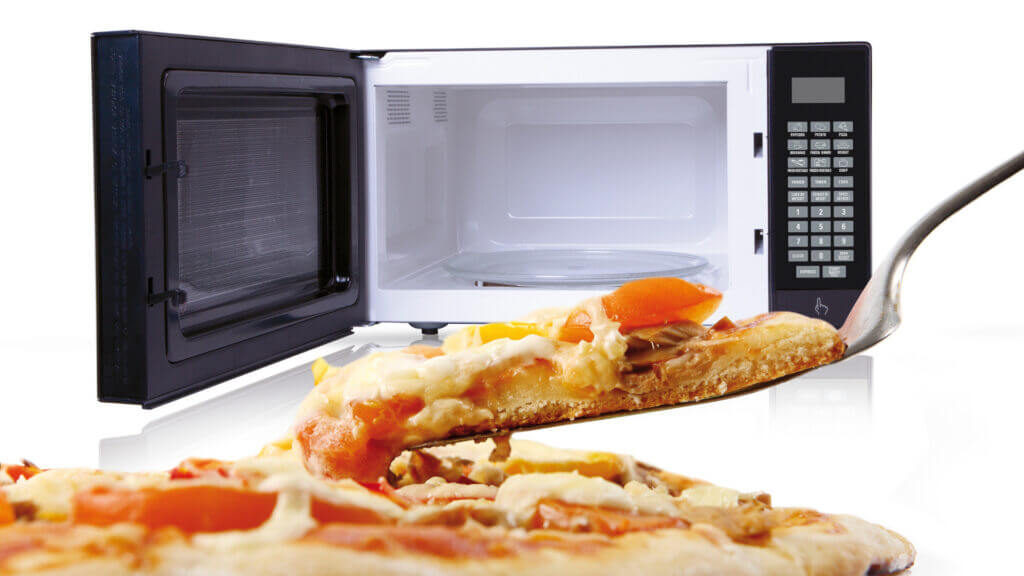 Pizza is in the foreground and it was cooked in an RV microwave convection oven which is in the background.