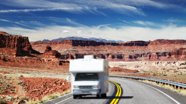 An RV drives down the highway in a blur in the desert (maybe Grand Canyon?). If you wanted to get one for a vacation, how much would it cost to rent an RV?