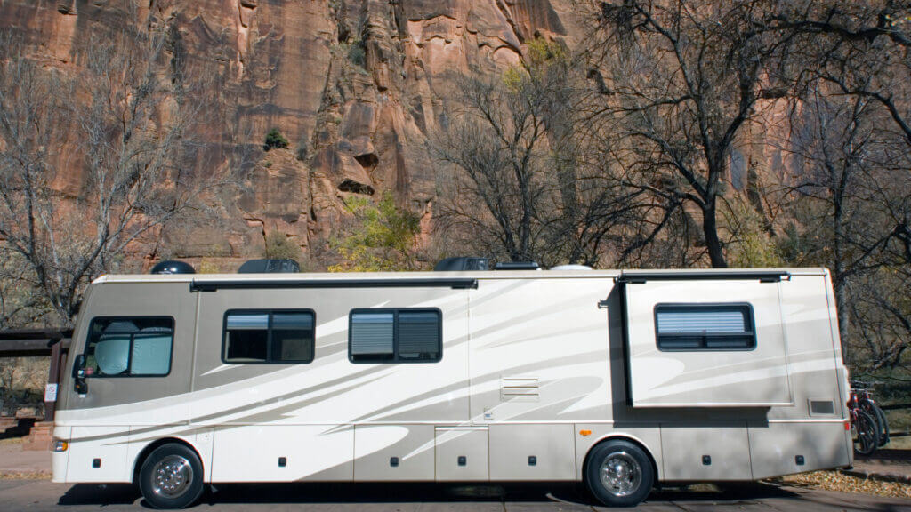 A large RV parked near a large rock wall is ready to try boondocking and use these tips for boondocking with a big RV. 