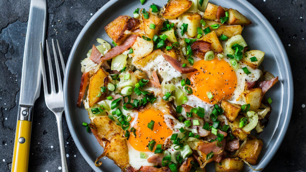 A breakfast hash of potatoes, onions, bacon, sausage, eggs, and spices is a delicious meal to be cooked on a blackstone griddle!
