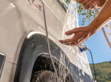 A hand tests the water temperature outside their RV after they finished installing a new tankless water heater into their RV.