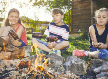 Kids sit in front of a campfire roasting hot dogs but can upgrade their campfire dinners with one of these recipes!