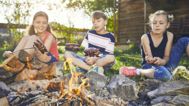 Kids sit in front of a campfire roasting hot dogs but can upgrade their campfire dinners with one of these recipes!