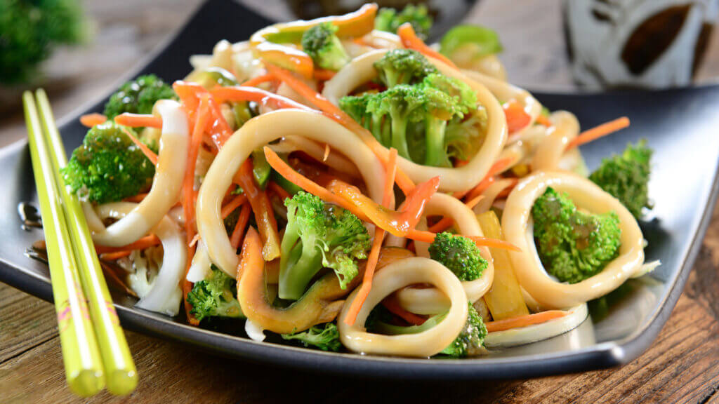 A veggie yakisoba dish fills a plate and is ready to be eaten with chopsticks! 