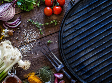 A blackstone griddle is surrounded by spices and veggies and ready to cook some delicious lunch recipes.
