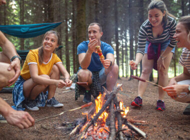 A group of friends cook some delicious lunches over the campfire.