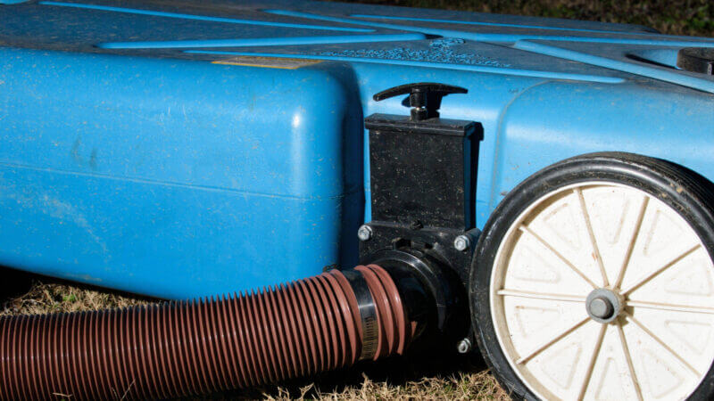 A Barker Portable RV waste tank is connected to the RV and known for it's blue color.
