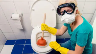 A woman wears a mask, gloves, and goggles to tackle the disgusting but necessary task of unclogging a toilet. How do you unclog an RV toilet?