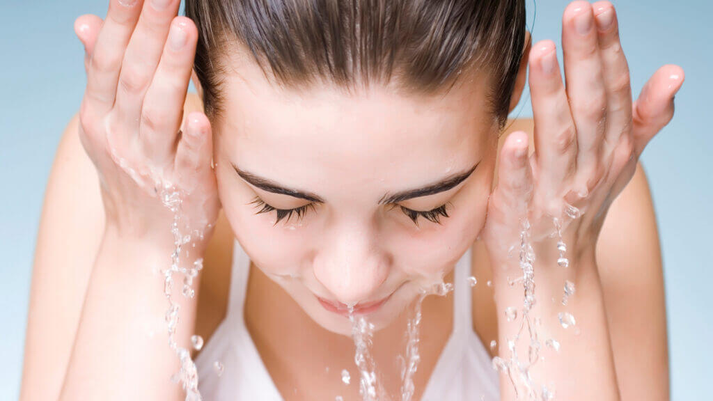 A woman washes her face and has softer skin thanks to the on the go water softener. 