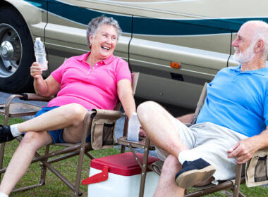 A couple sits outside their RV on a hot day and try to keep cool with cold water.