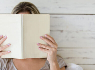 Ready to hit the road? A woman hides her face in an RV book to learn all she needs to know.