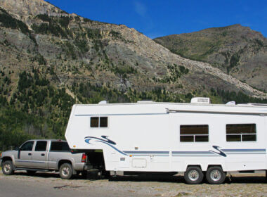 A large truck is needed to tow a fifth wheel, which is the best? This truck tows a fifth wheel alongside some brown hills.