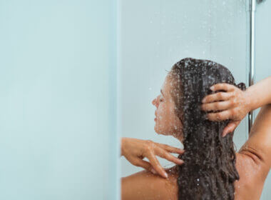 A woman showers and her water pressure is perfect because she is using the Renator M11 Water Pressure Regulator.