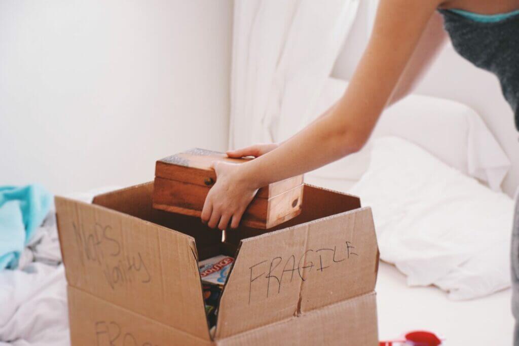 a woman packing a box that says "fragile" as she prepares for full-time rv living