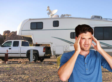 A man cringes because he regrets buying a fifth wheel RV that is now parked in the desert.
