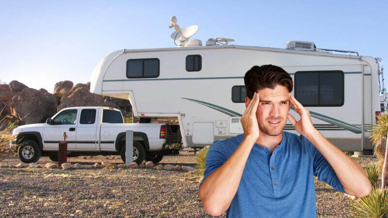 A man cringes because he regrets buying a fifth wheel RV that is now parked in the desert.