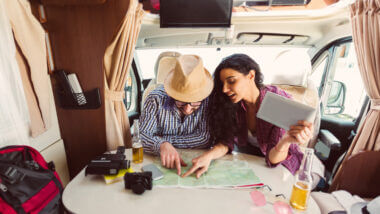 A couple fixate on a map as they drink beers and plan their first RV cross country trip.