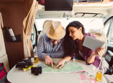 A couple fixate on a map as they drink beers and plan their first RV cross country trip.