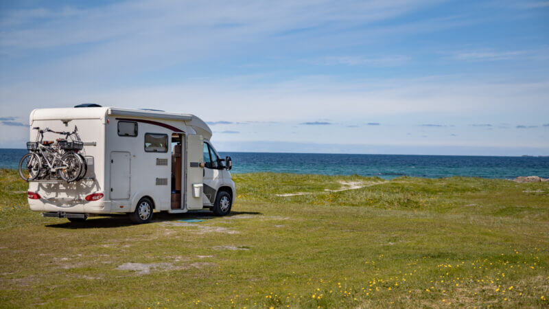 An RV is parked in an empty field for dispersed camping along the ocean coast.