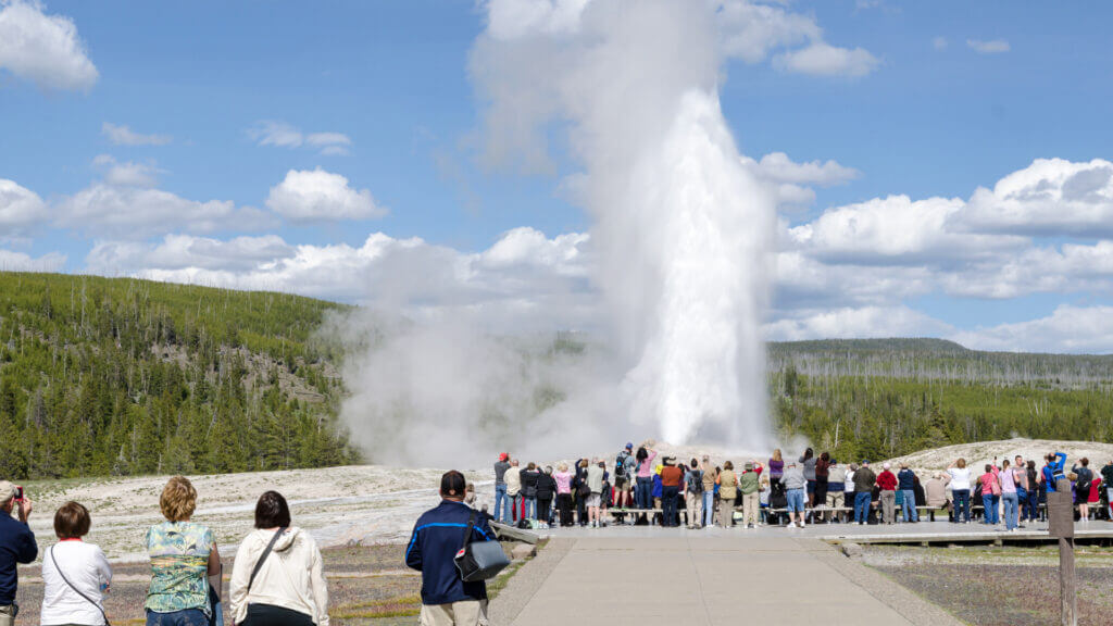 A crowd surrounds a geyser in Yellowstone National Park.