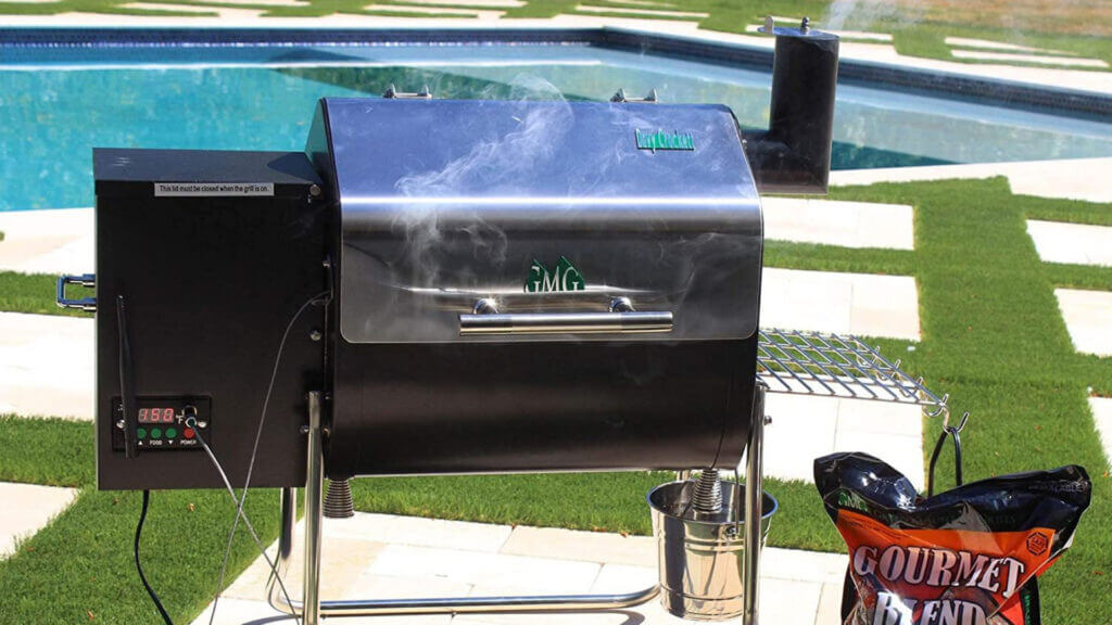 A green mountain grill davy crockett pellet grill smokes food near a pool.
