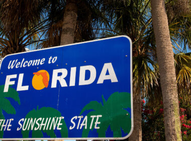 Florida sign for the sunshine state set against some palm trees. Where are the best free camping spots in Florida?