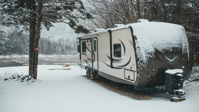 An RV is covered in snow and needs help to stay warm.