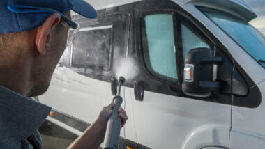 A man hoses down an RV and uses some of the best RV cleaning products to keep his RV in tip top shape.