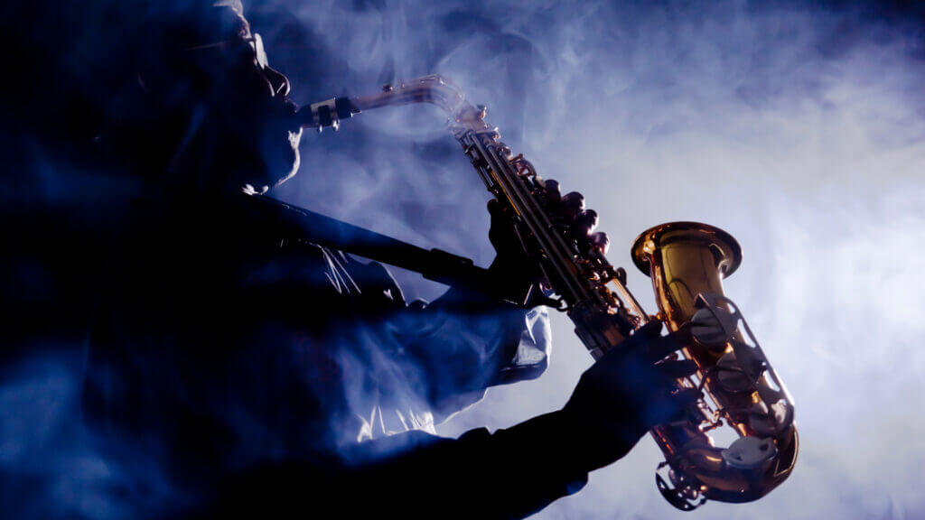 A Jazz musician plays the saxophone in a smoky jazz club.