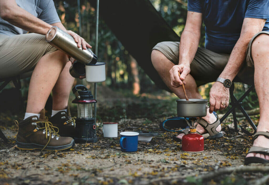 Men enjoying camping dessert recipes in the woods.